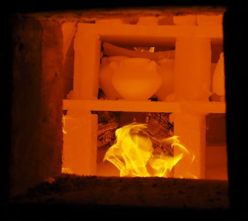 Inside the kiln, Additional coals from side stoking can be see behind the flames. 