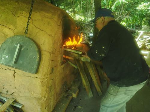 Stoking the kiln via side ports to raise the temperature and introduce ash into the rear of the kiln